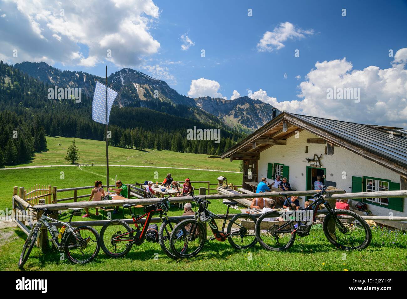 Gli ospiti si siedono a Vorderalm con Hochgern sullo sfondo e mountain bike in primo piano, Vorderalm, Hochgern, Alpi Chiemgau, Salzalpensteig, Baviera superiore, Baviera, Germania Foto Stock
