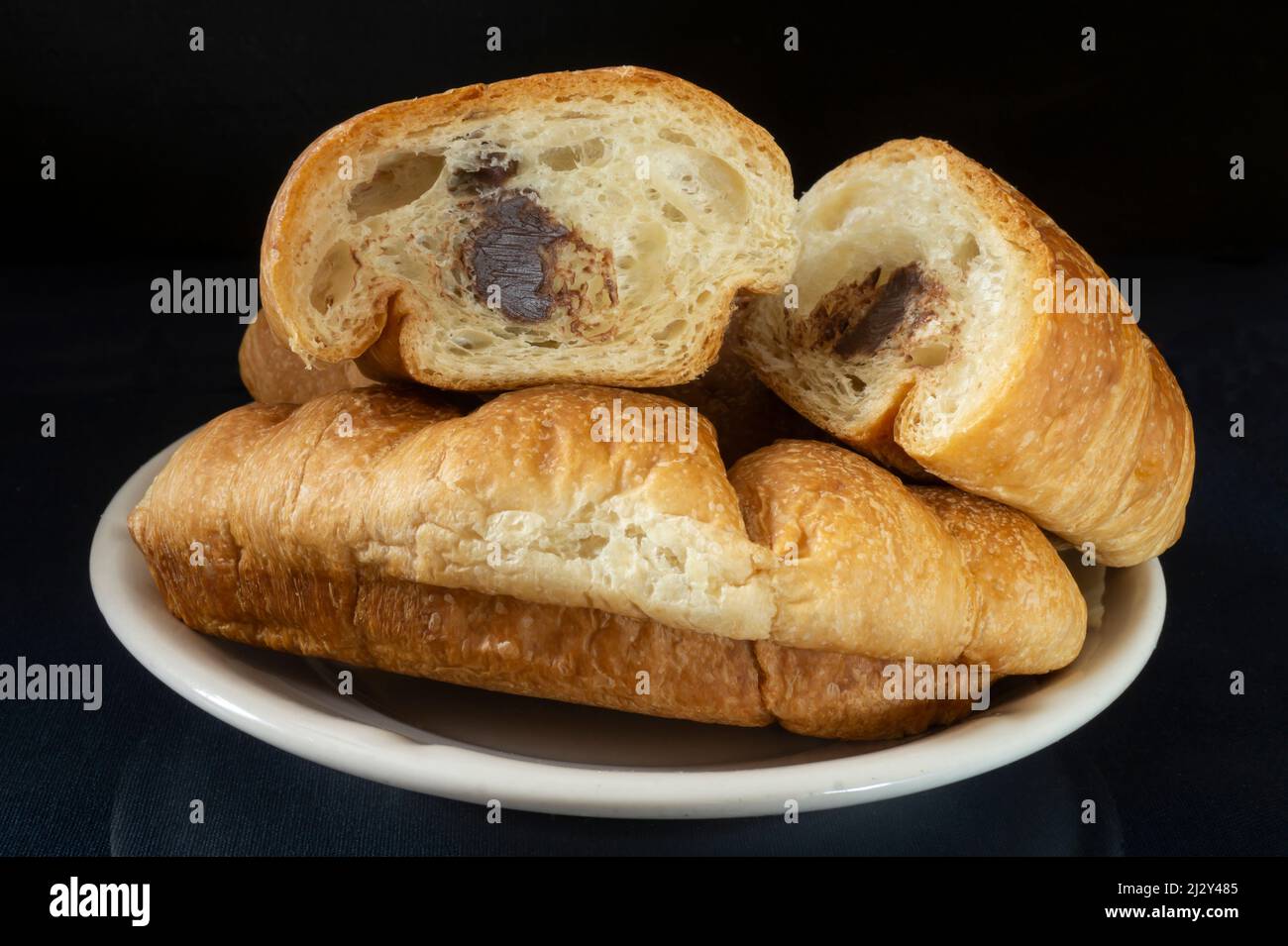 Croissant in un piatto bianco sul tavolo. Cibo su sfondo nero Foto Stock