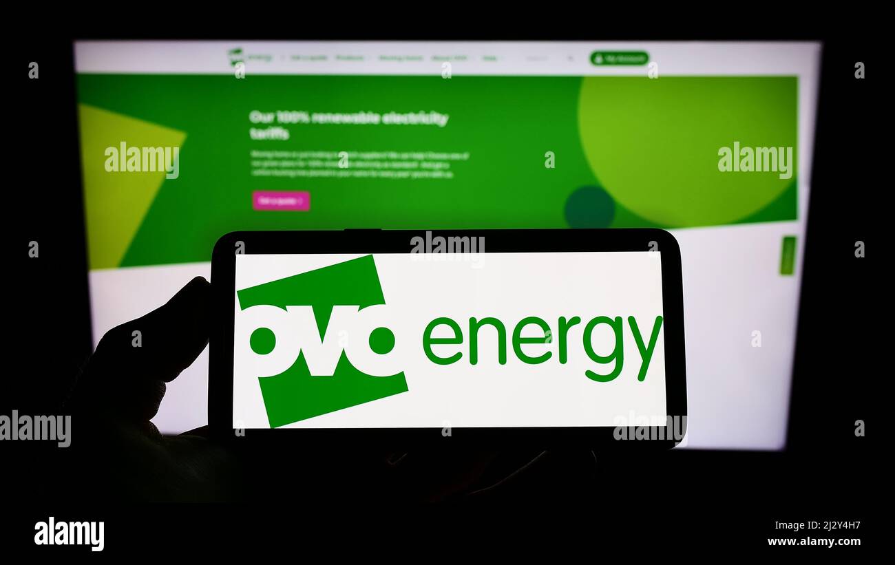 Persona che tiene il telefono cellulare con il logo della società di utilità britannica OVO Energy Ltd sullo schermo di fronte alla pagina web aziendale. Mettere a fuoco sul display del telefono. Foto Stock