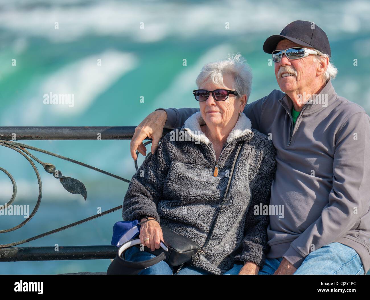 Felice, anziano, coppia di nonni che visitano e siedono su una panchina del parco alle Cascate del Niagara in Brampton Ontario Canada. Foto Stock