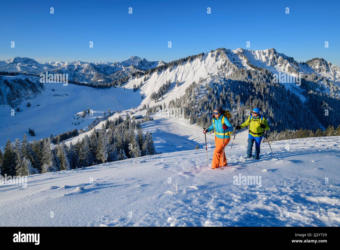 Uomo e donna che camminano sulla montagna innevata, sulle Alpi bavaresi e Rofan sullo sfondo, Brecherspitze, Spitzing area, Alpi bavaresi, alta Baviera, Baviera, Germania Foto Stock