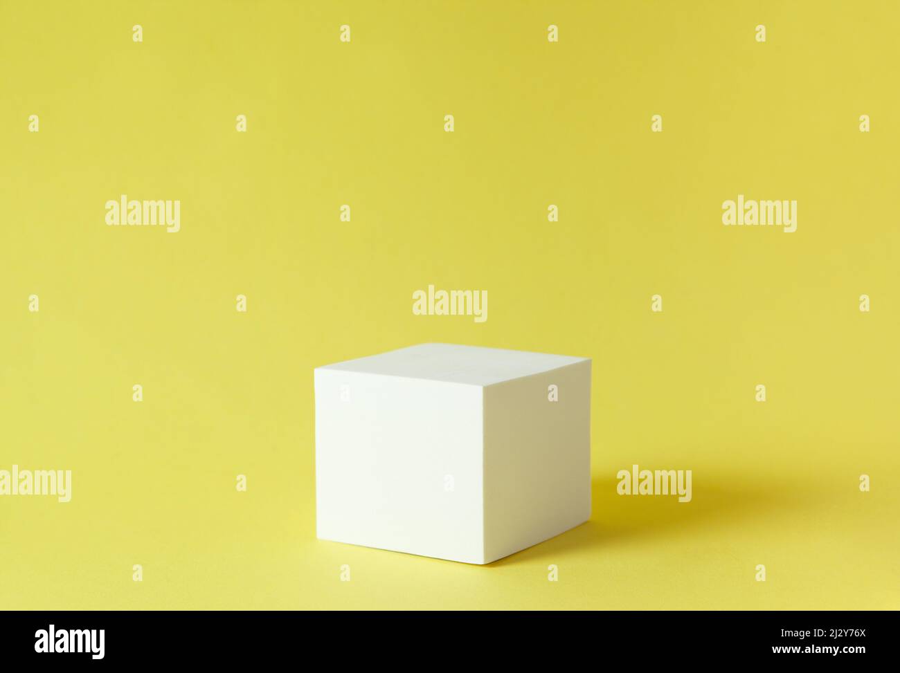 cubo bianco su sfondo giallo. podio per la presentazione Foto Stock