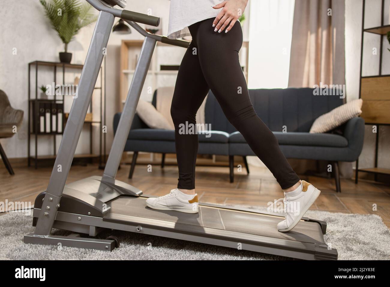 Atletica giovane donna sportiva che fa esercizio cardio a casa. Fitness  ragazza sport donna in esecuzione sul tapis roulant al coperto. Primo piano  di scarpe da ginnastica femminili da piedi, tapis roulant