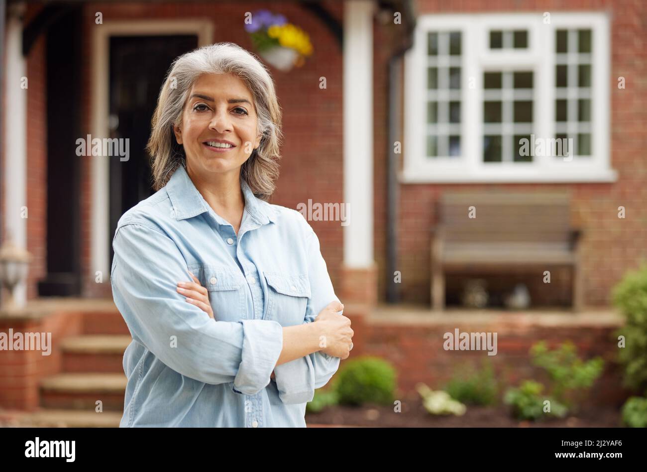 Ritratto di donna matura in piedi nel giardino davanti a casa da sogno in campagna Foto Stock