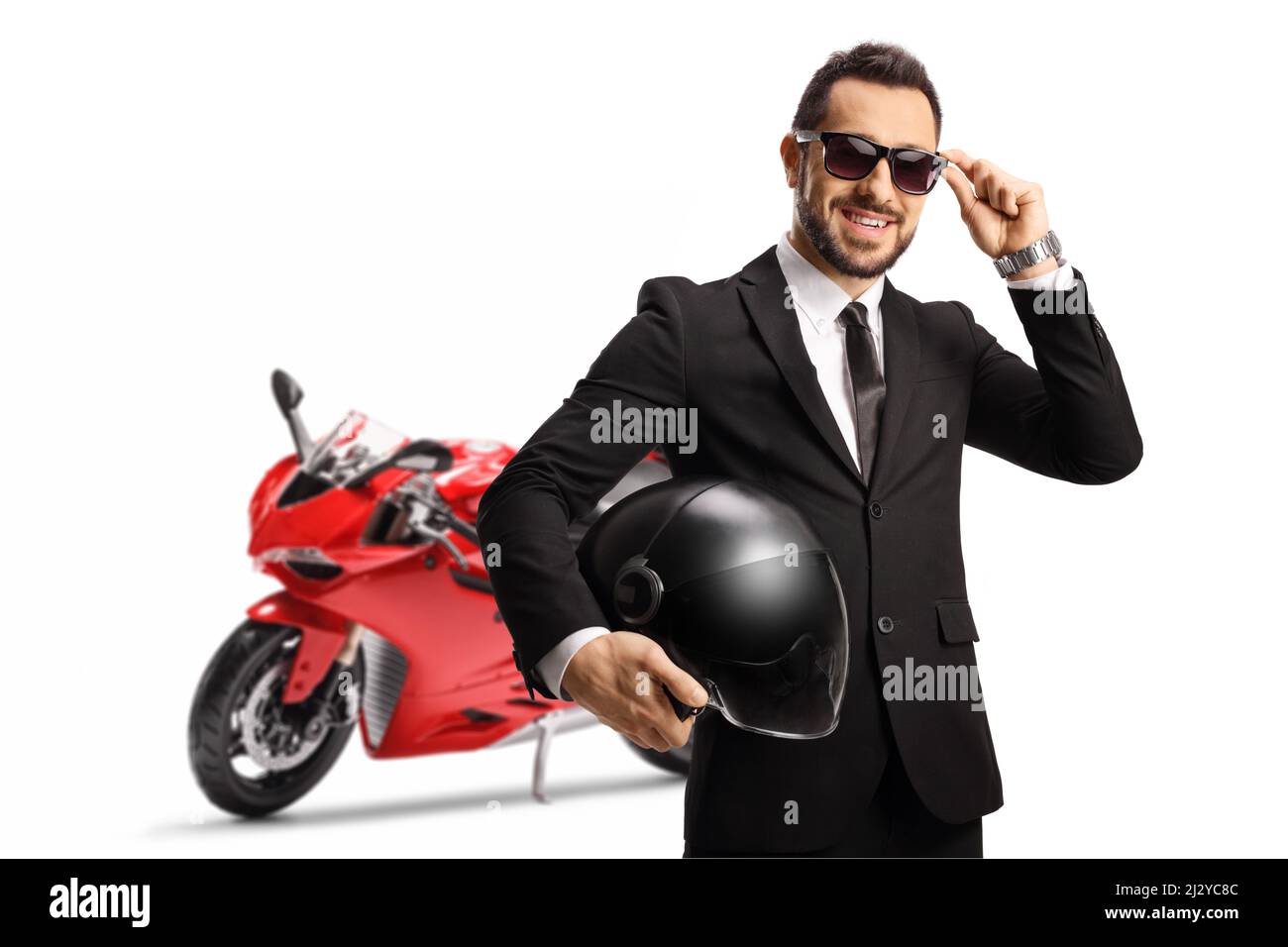 Uomo d'affari con una moto da corsa rossa che tiene un casco e indossa occhiali da sole isolati su sfondo bianco Foto Stock