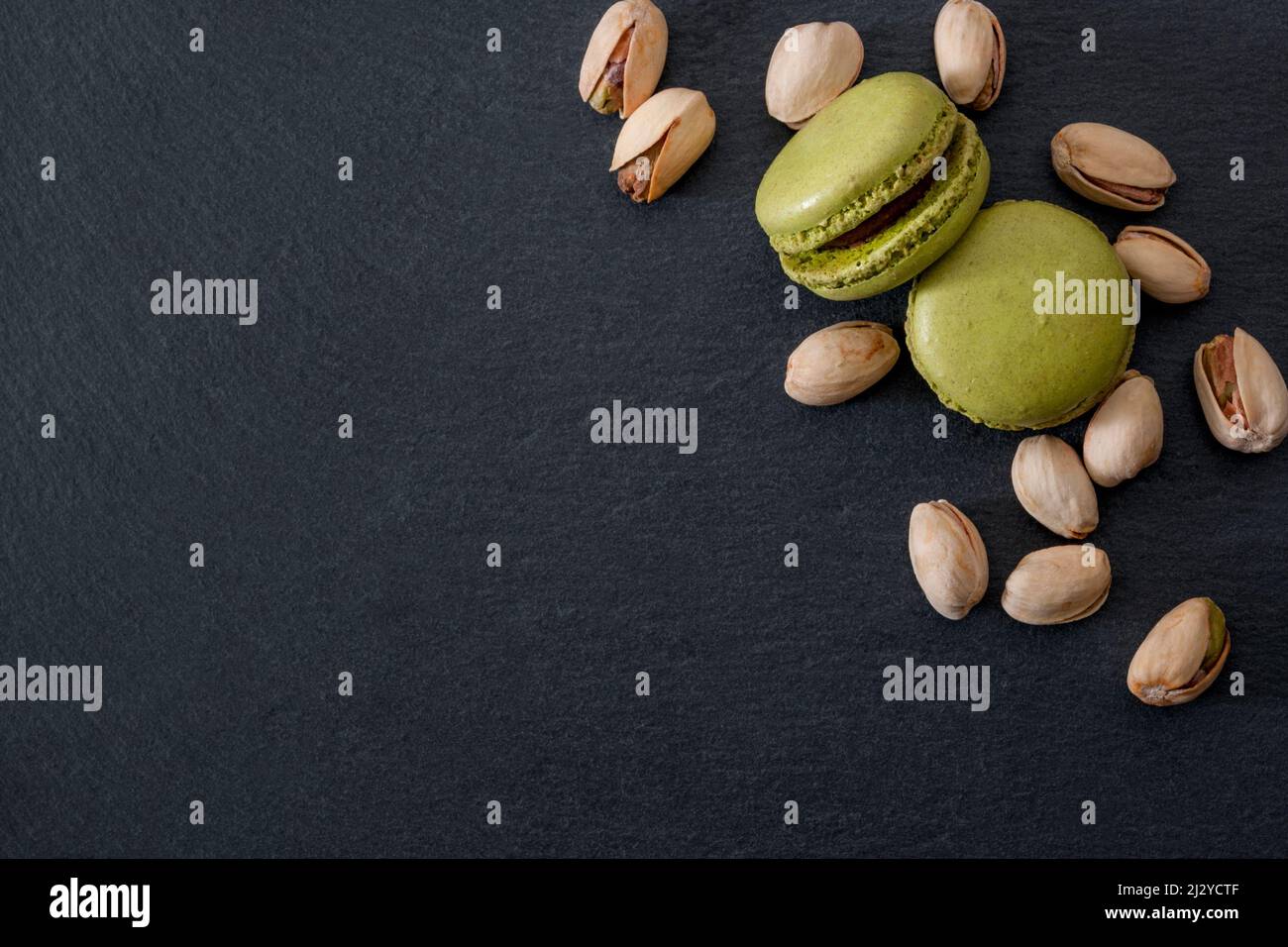 Dessert francese, dolciumi a base di meringa dolce e dolci costosi con macaroon o macaron al pistacchio verde con un mazzo di pugnali Foto Stock