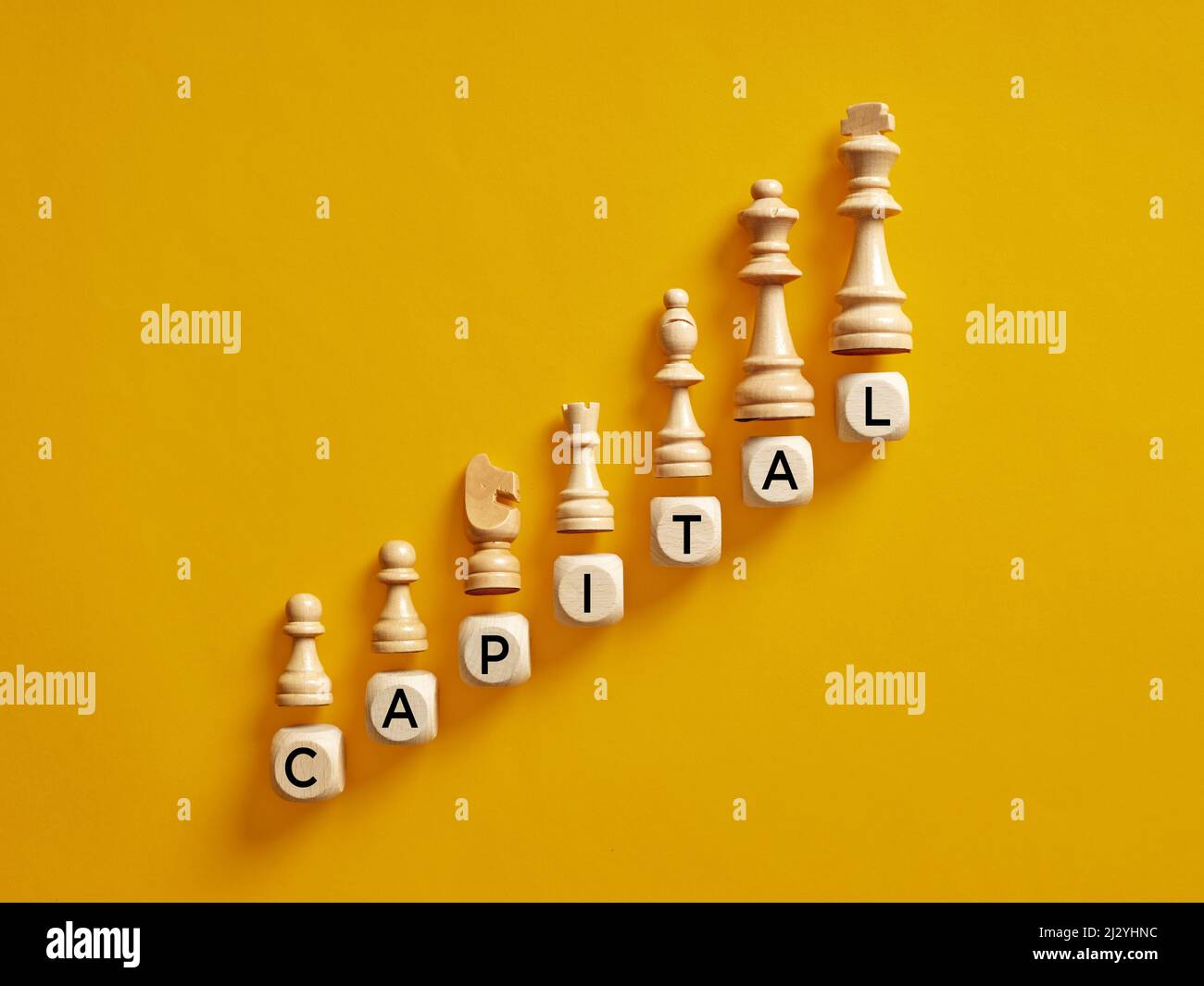 La parola capitale su cubi di legno con pezzi di scacchi. Aumentare il concetto di accumulo di capitale. Foto Stock