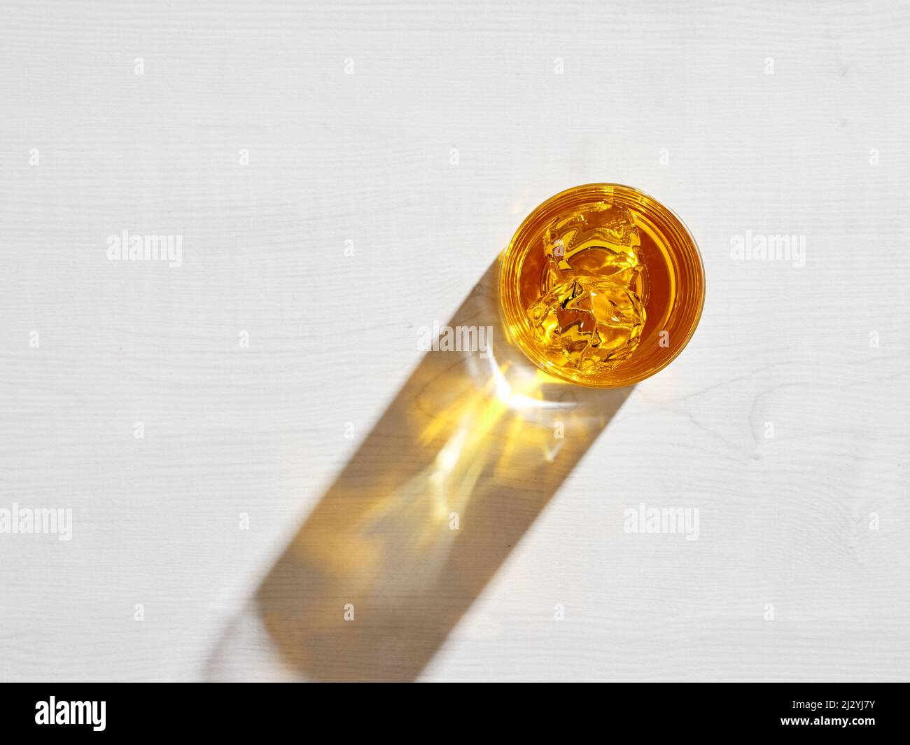 Bicchiere di elegante whiskey con ghiaccio su sfondo testurizzato e luce dura. Concetto di bevanda analcolica. Foto Stock