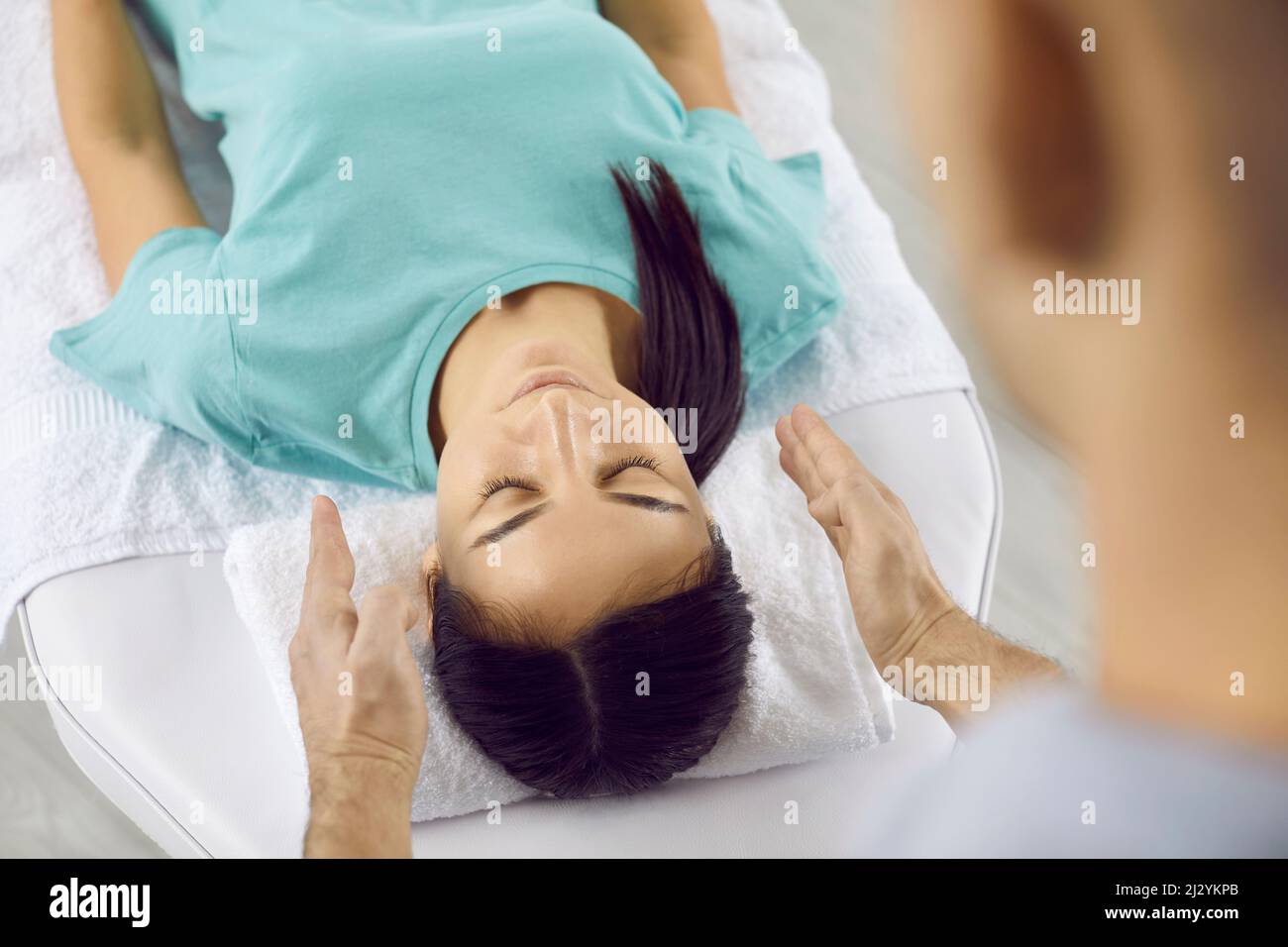 Giovane donna che si rilassa durante una sessione di terapia olistica con specialista di guarigione Reiki Foto Stock