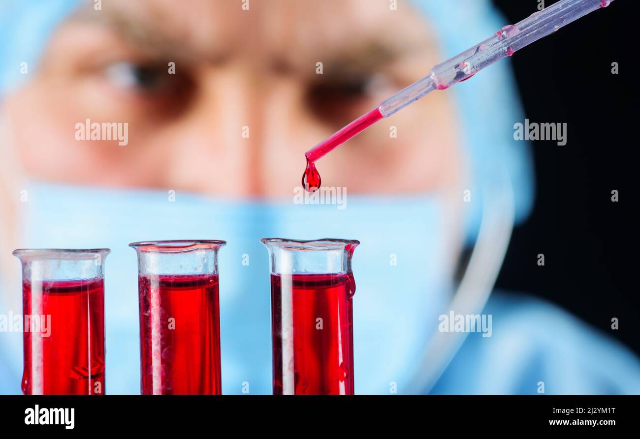 Tecnico di laboratorio con campioni di sangue che effettua la ricerca. Medico o ricercatore con provette Foto Stock