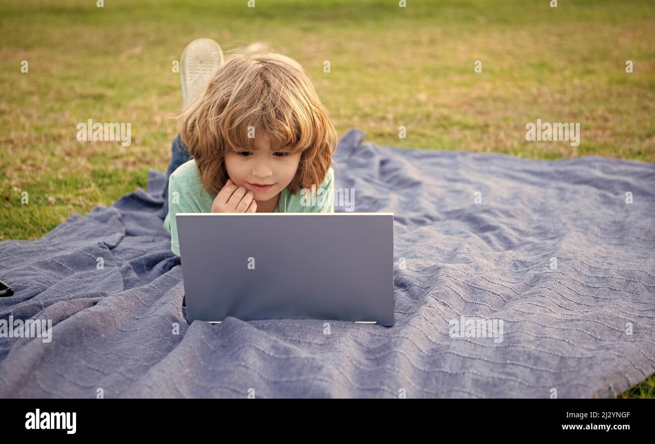 Ragazzo bambino utilizzare laptop computer apprendimento tecnologia rilassante su coperta naturale all'aperto, corsi on-line Foto Stock