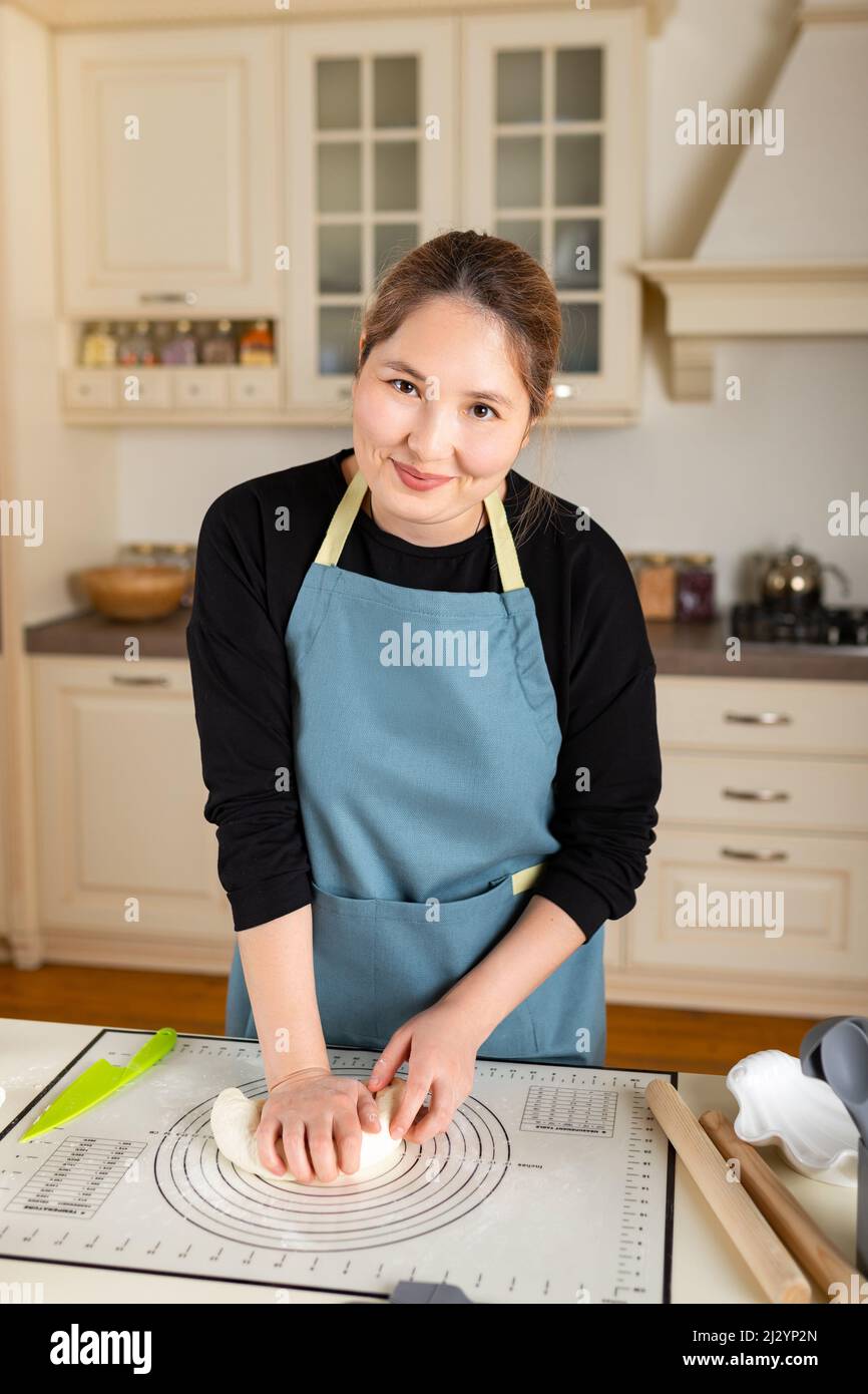 Giovane felice sorridente kazako donna ritratto cottura da pasta in cucina moderna, guardare la macchina fotografica. Foto Stock