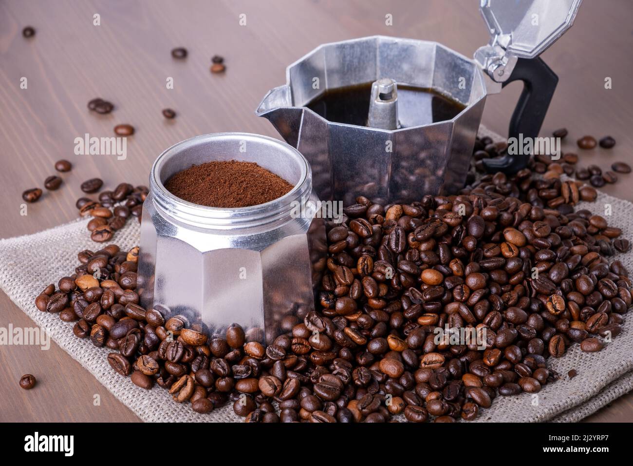 Macchina per caffè geyser disassemblata su superficie in legno. Chicchi di caffè. Foto Stock