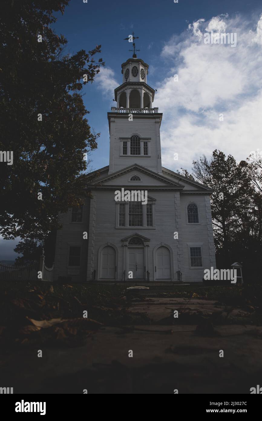 Un colpo verticale della vecchia prima chiesa congregazionale in Vermont su sfondo blu cielo nuvoloso Foto Stock