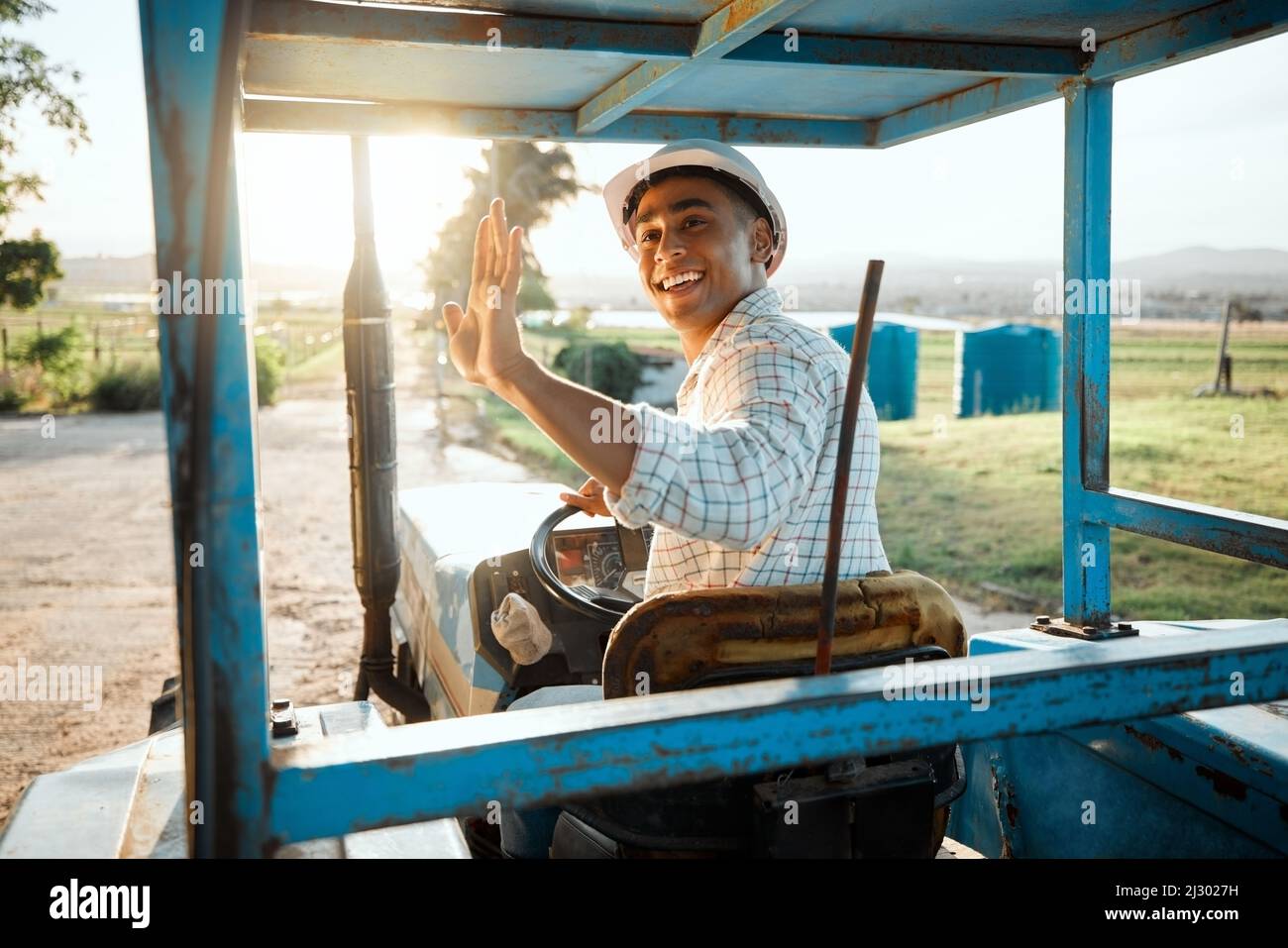 Fuori per controllare sul resto dei miei raccolti. Shot di un giovane agricoltore che guida un trattore in un'azienda agricola. Foto Stock