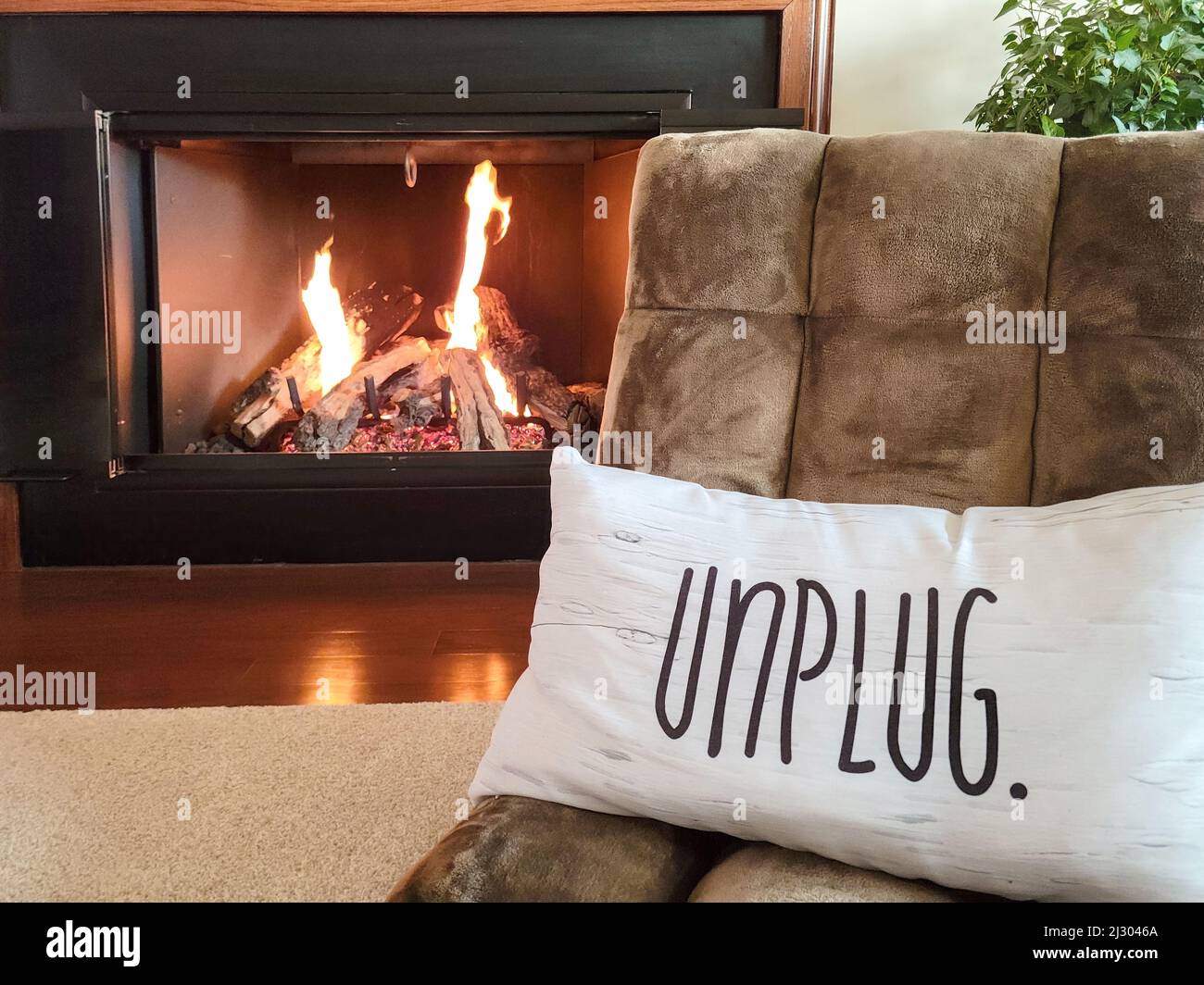 Sedia da pavimento marrone con cuscino bianco accanto al caminetto Foto Stock