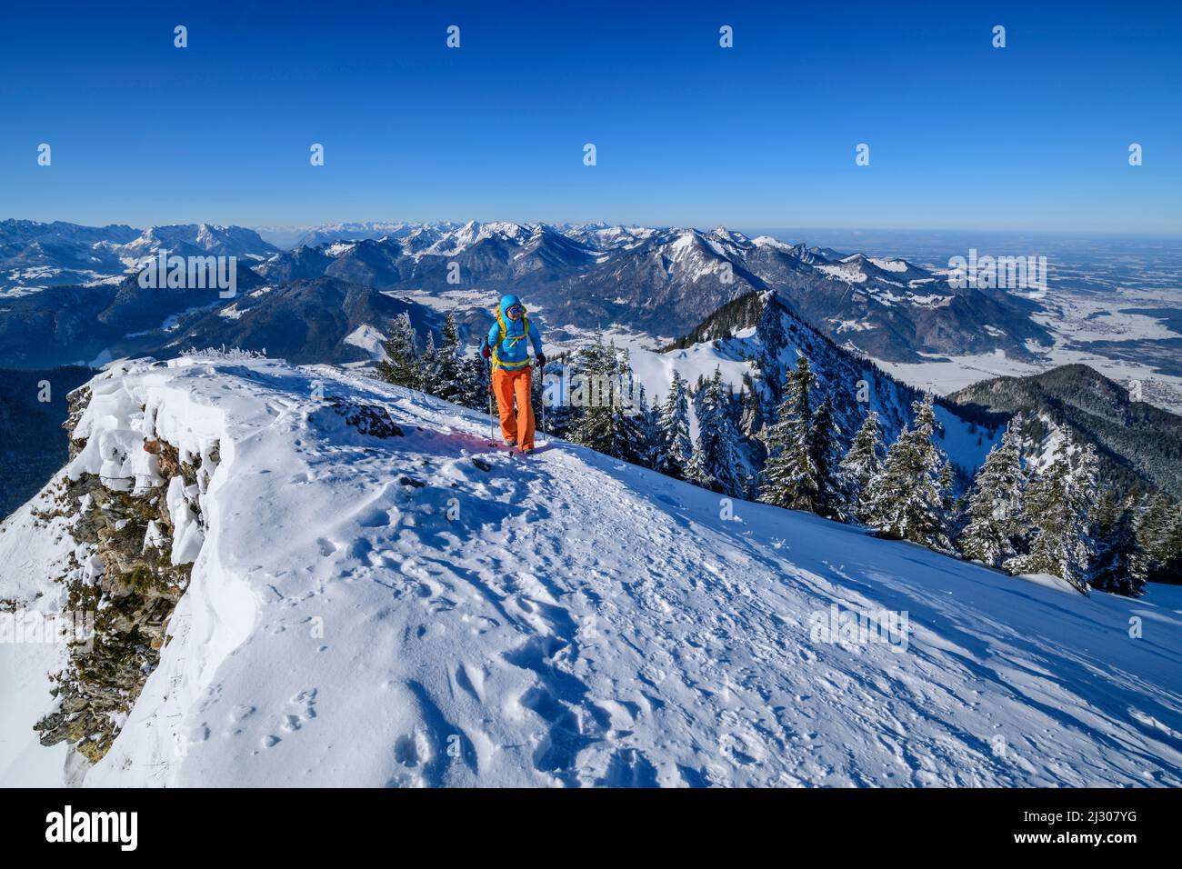 L'escursionismo femminile sale su un pendio innevato fino a Hochgern, Alpi del Chiemgau sullo sfondo, Hochgern, Alpi del Chiemgau, alta Baviera, Baviera, Germania Foto Stock