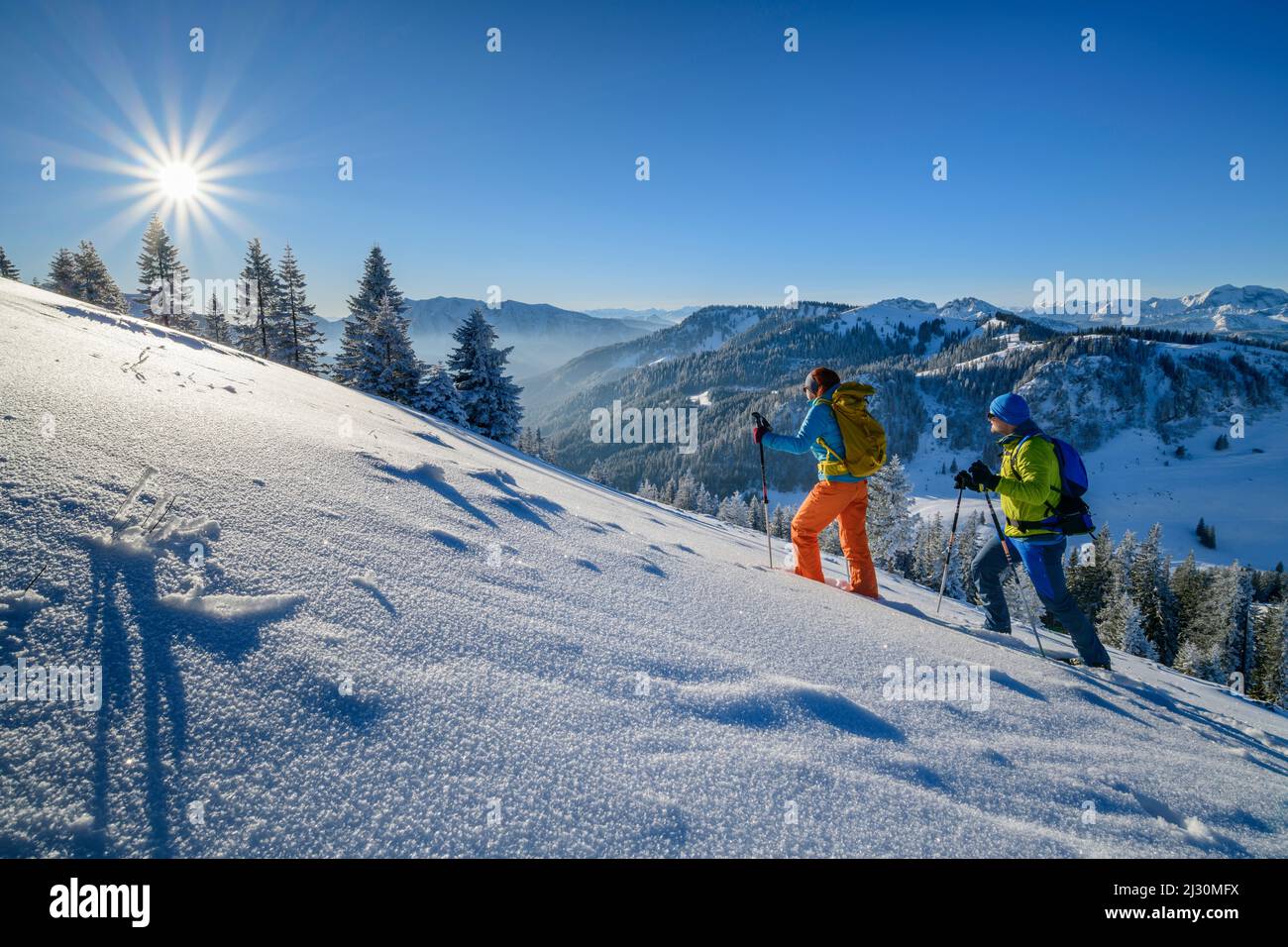 Uomo e donna che camminano su un pendio innevato, Alpi bavaresi sullo sfondo, Brecherspitze, Spitzing, Alpi bavaresi, alta Baviera, Baviera, Germania Foto Stock