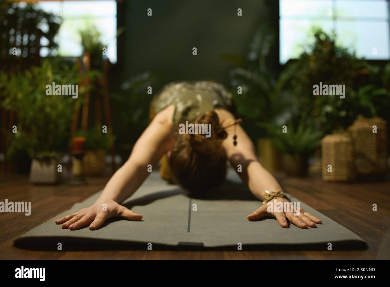 Primo piano su donne con tappeto yoga fare yoga nel verde soggiorno. Foto Stock