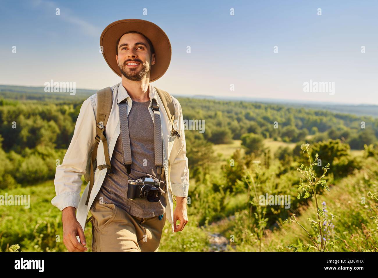 Ritratto di escursionista maschile con fotocamera e zaino godendo perfetto tempo estivo Foto Stock