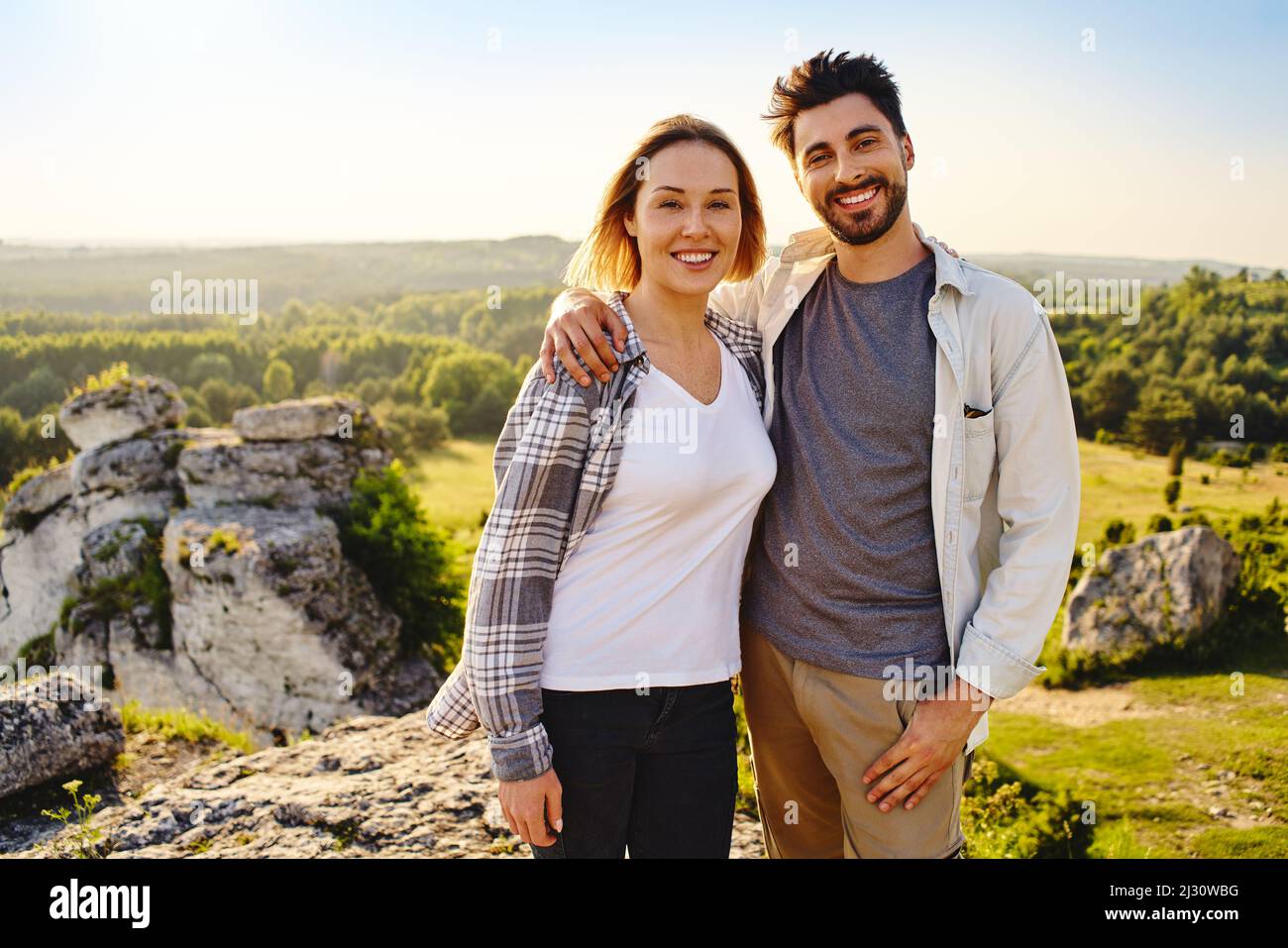 Ritratto di giovane coppia felice in piedi insieme con paesaggio di campagna dietro di loro durante l'escursione estiva Foto Stock