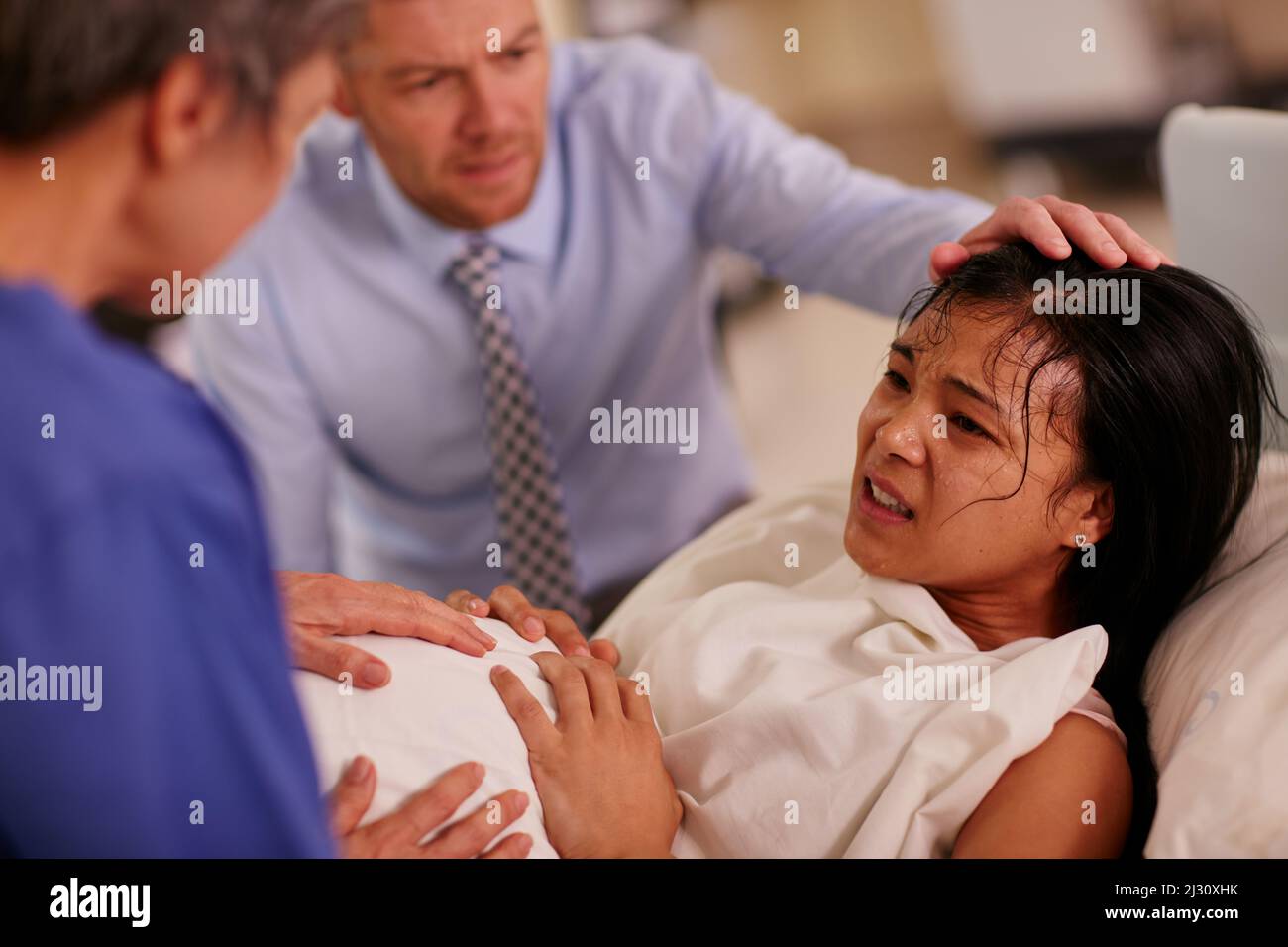 Dare alla luce può essere difficile, ma così siete voi. Scatto di una giovane donna che partorisce con il marito che la sostiene sullo sfondo. Foto Stock