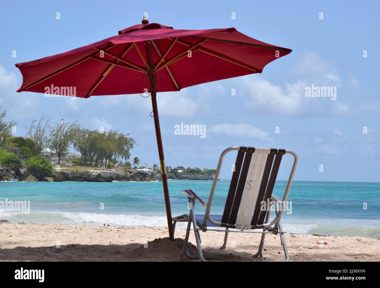 Ombrellone con sedie sulla spiaggia di sabbia soleggiata con acqua turchese. Foto Stock