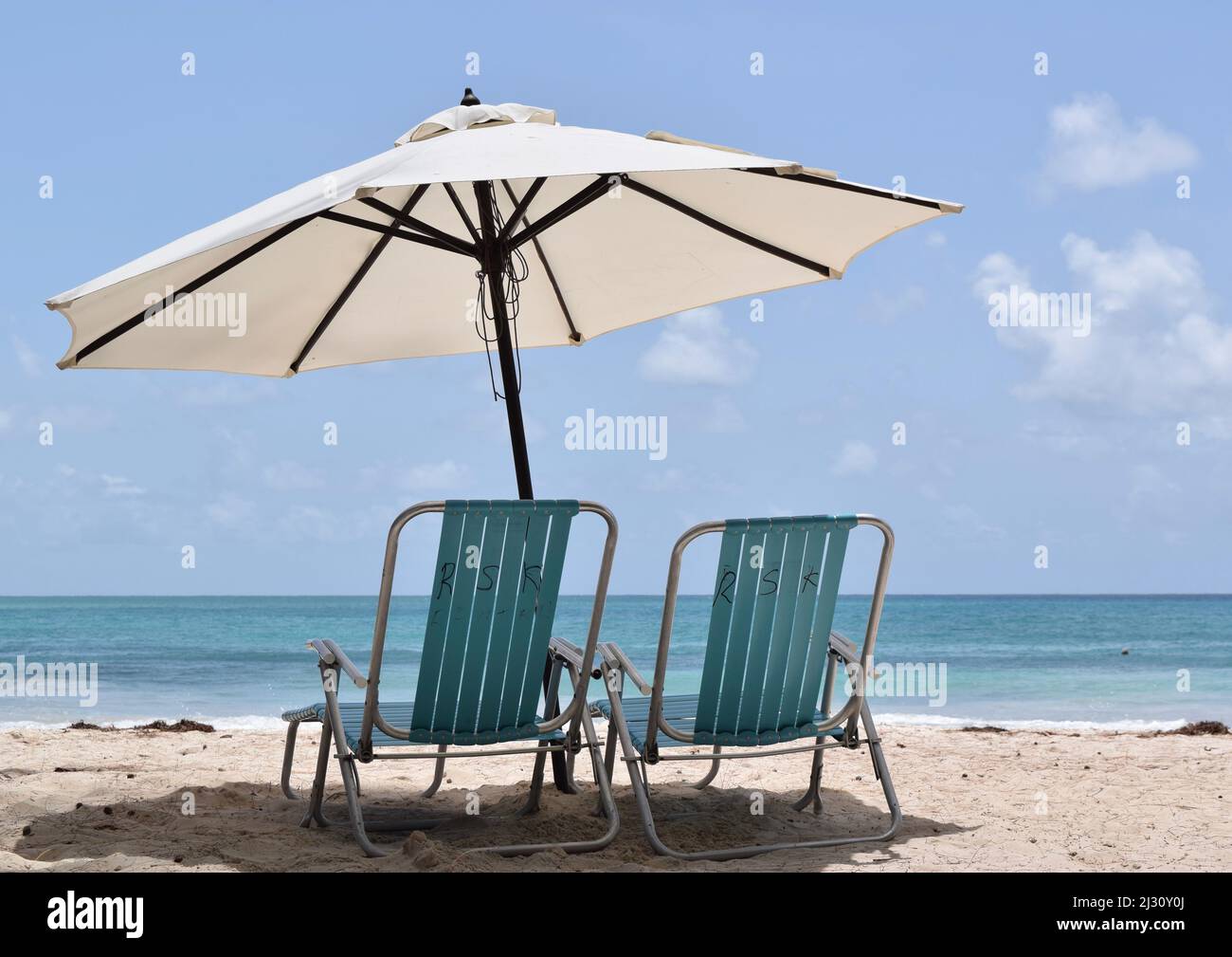 Ombrellone con sedie sulla spiaggia di sabbia soleggiata con acqua turchese. Foto Stock