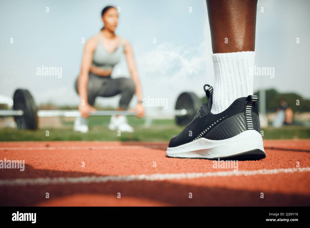 Si impegna per il fitness. Primo piano di un atleta maschile irriconoscibile in piedi fuori, mentre una donna si esercita con pesi in background. Foto Stock