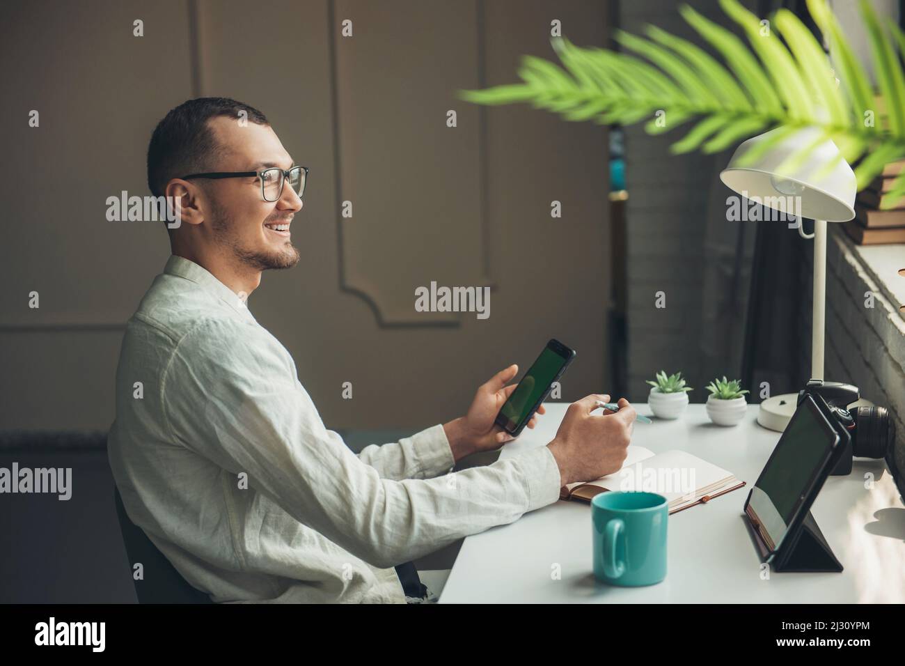 Vista laterale di un uomo studente che utilizza un moderno tablet digitale facendo appunti scrivendo in studio notebook online. Connessione online. Marketing digitale. Affari Foto Stock