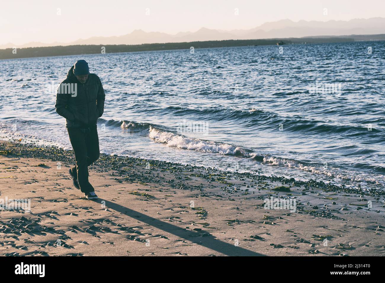 Uomo che cammina sulla spiaggia e lotta emotivamente. Uomo che lotta e cammina. Ragazzo che ha un duro tempo nella vita. Tempi duri nella vita dell'uomo. Foto Stock