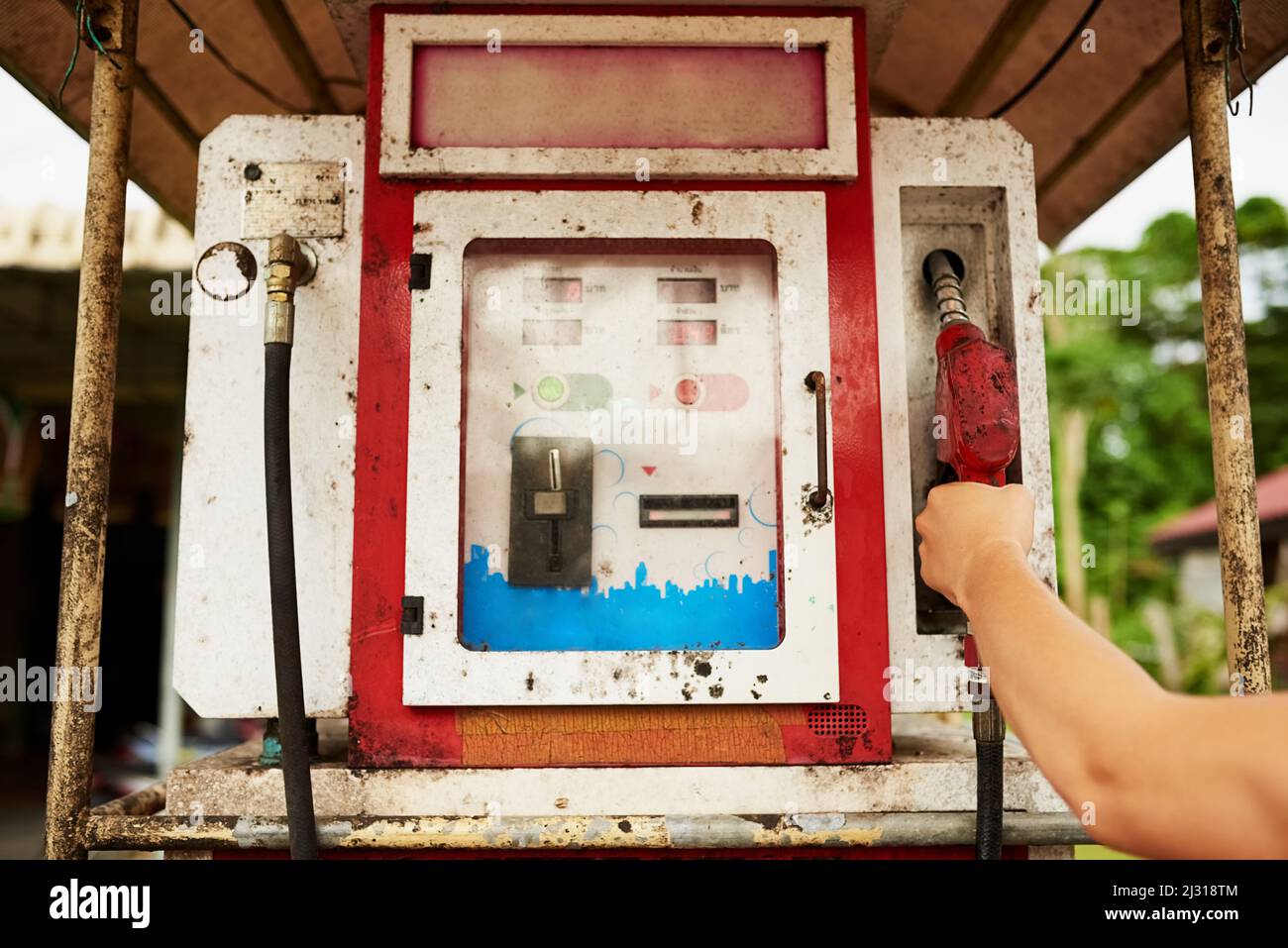 Riempire. Scatto corto di un uomo che usa una vecchia pompa ad una stazione di benzina. Foto Stock