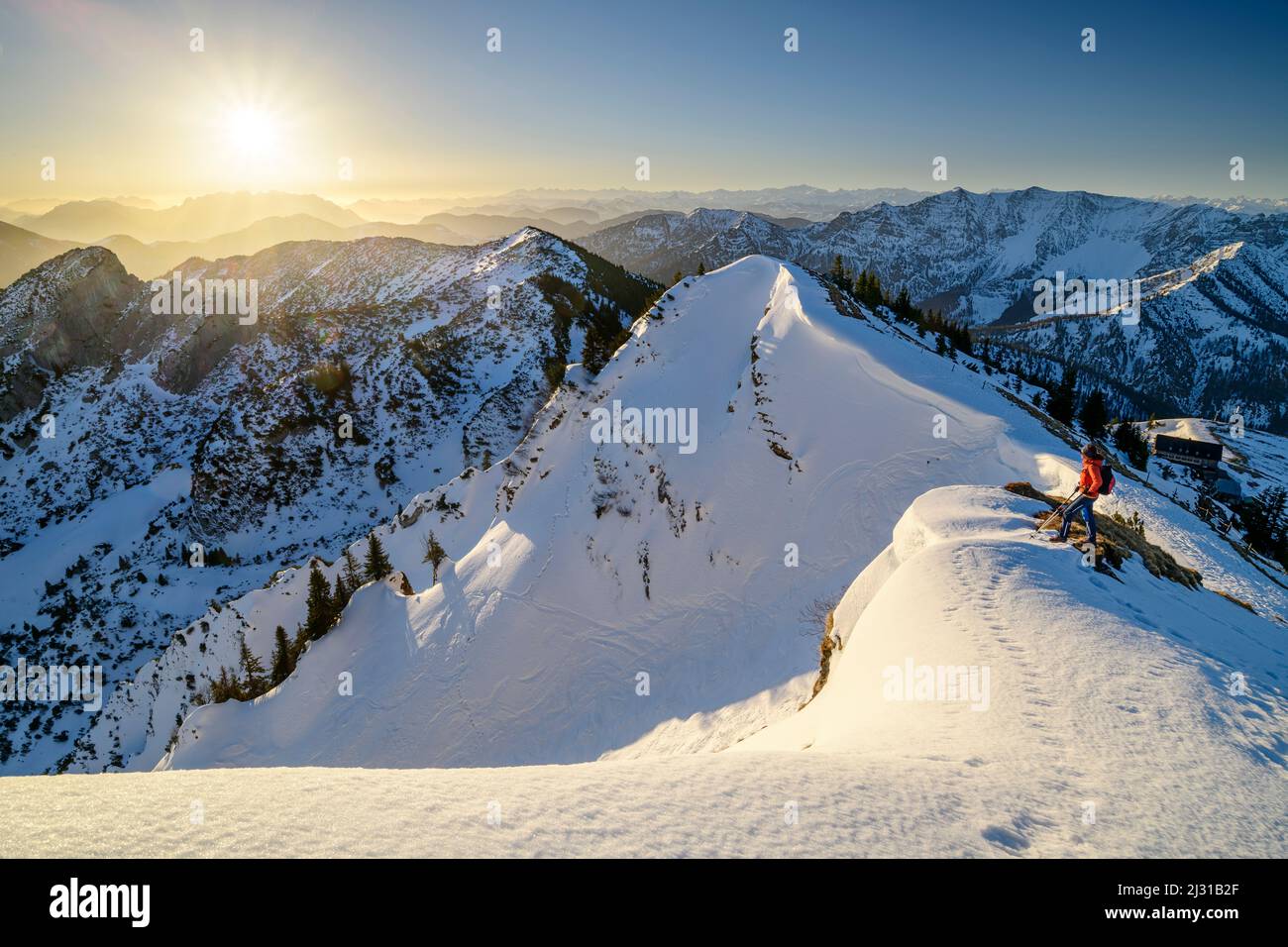 Donna escursionismo si erge su un crinale innevato e guarda alle Alpi bavaresi e Chiemgau, Rotwand, Spitzing, Alpi bavaresi, alta Baviera, Baviera, Germania Foto Stock