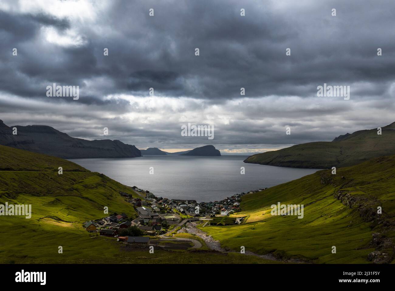 Vista sul villaggio di pescatori Kvivik, Streymoy, Faeroer. Nuvole scure profonde, nubi, mare sullo sfondo. Foto Stock