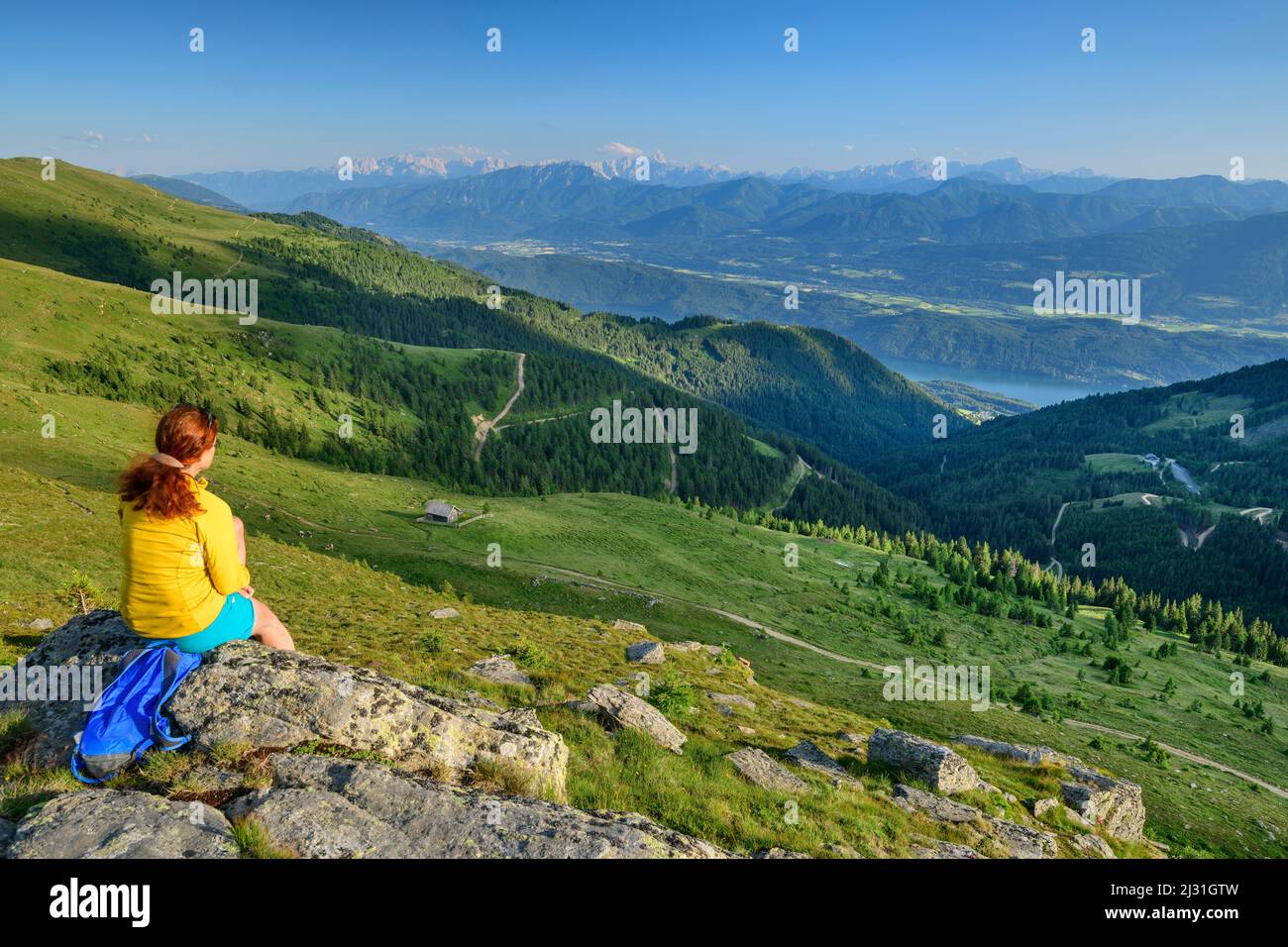 Donna mentre escursioni si siede sulla roccia e guarda verso la valle, Kampnock, Nockberge, Nockberge-Trail, Unesco Nockberge Biosphere Park, Gurktal Alpi, Carinzia, Austria Foto Stock