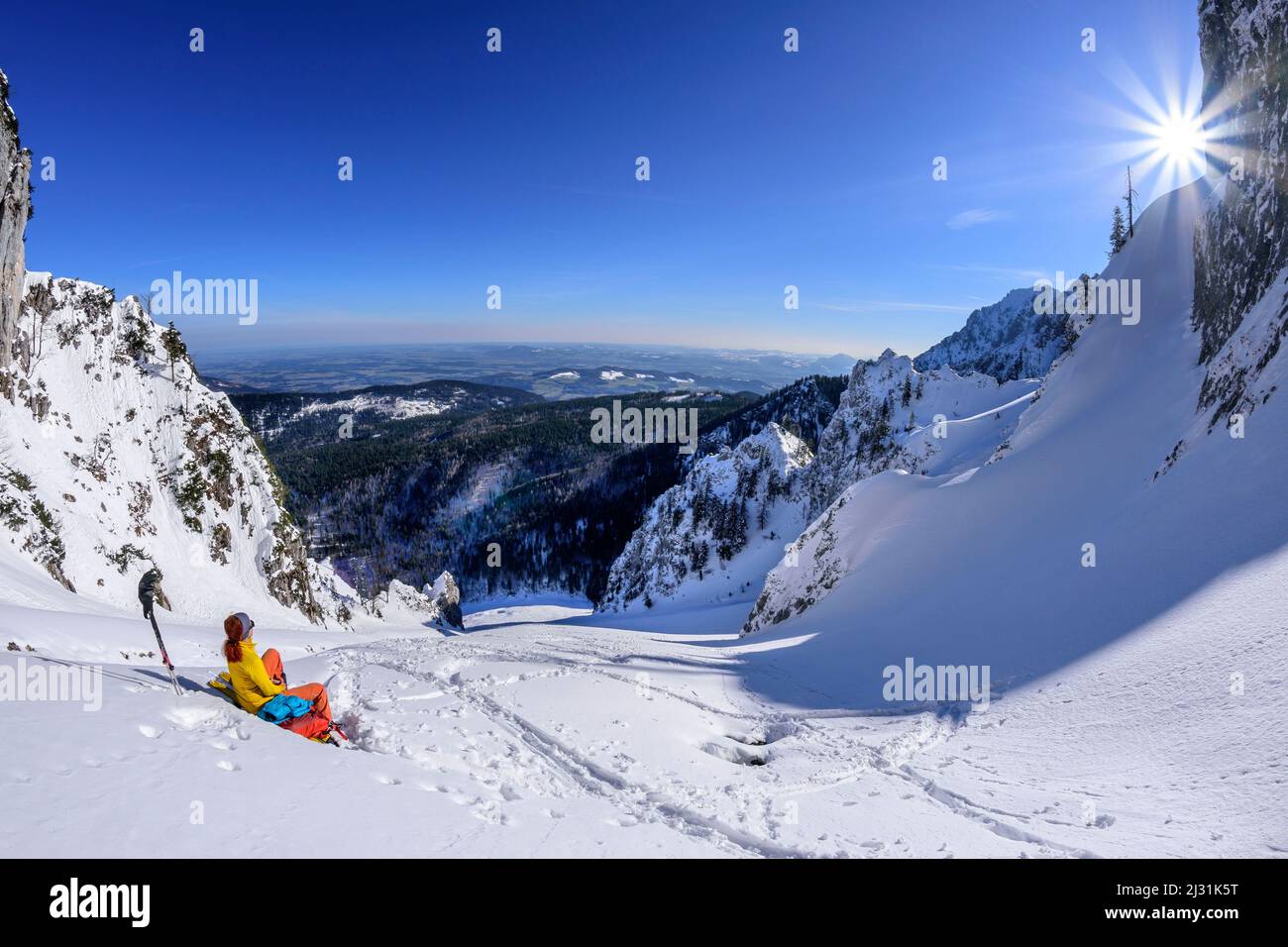 Donna in giro sci fa una pausa in una grande neve auto, Zwiesel, Alpi Chiemgau, alta Baviera, Baviera, Germania Foto Stock