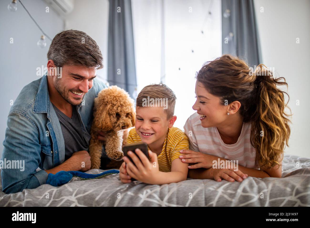 Felice famiglia con i dispositivi moderni e cane divertirsi, giocando a casa Foto Stock