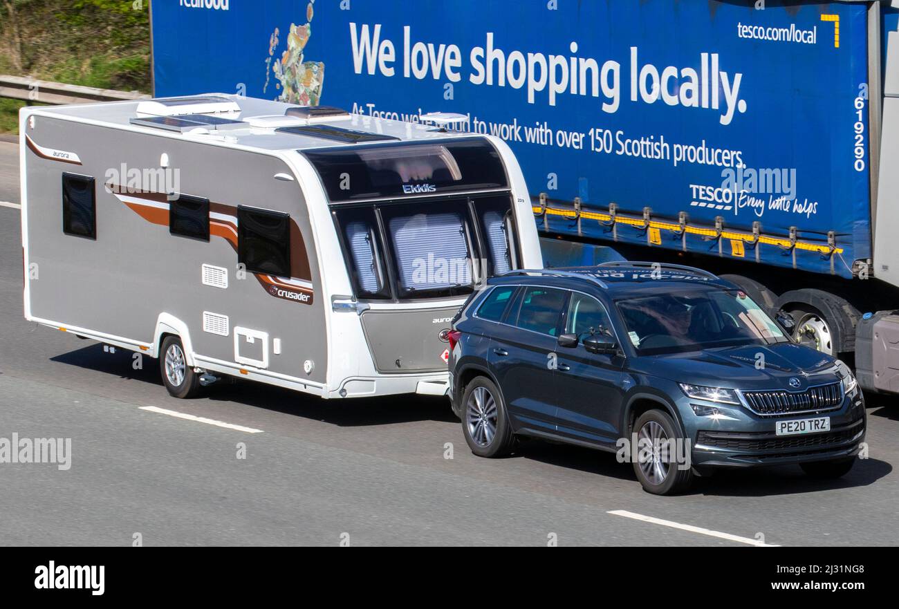 2020 grigio Skoda K0DIAQ 1968cc 7 velocità di traino automatico Elddis Crusder caravan mentre sorpassi Tesco camion alimentari a bordo di un supermercato sull'autostrada M61 Foto Stock