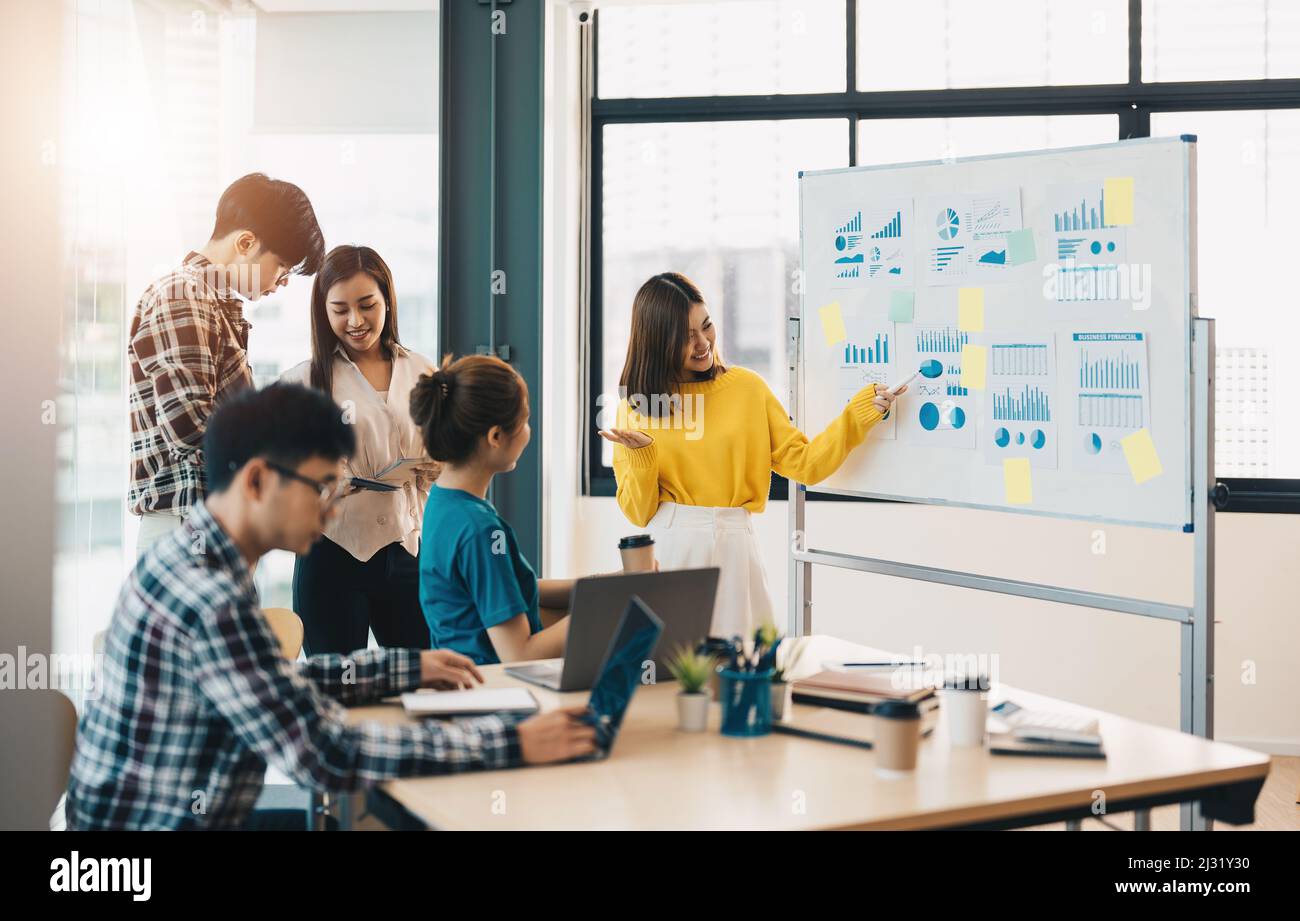 gruppo di giovani asiatici creativi che fanno il brainstorming incontrare colleghi in sala di discussione progetto. donna in piedi alla lavagna dare Foto Stock