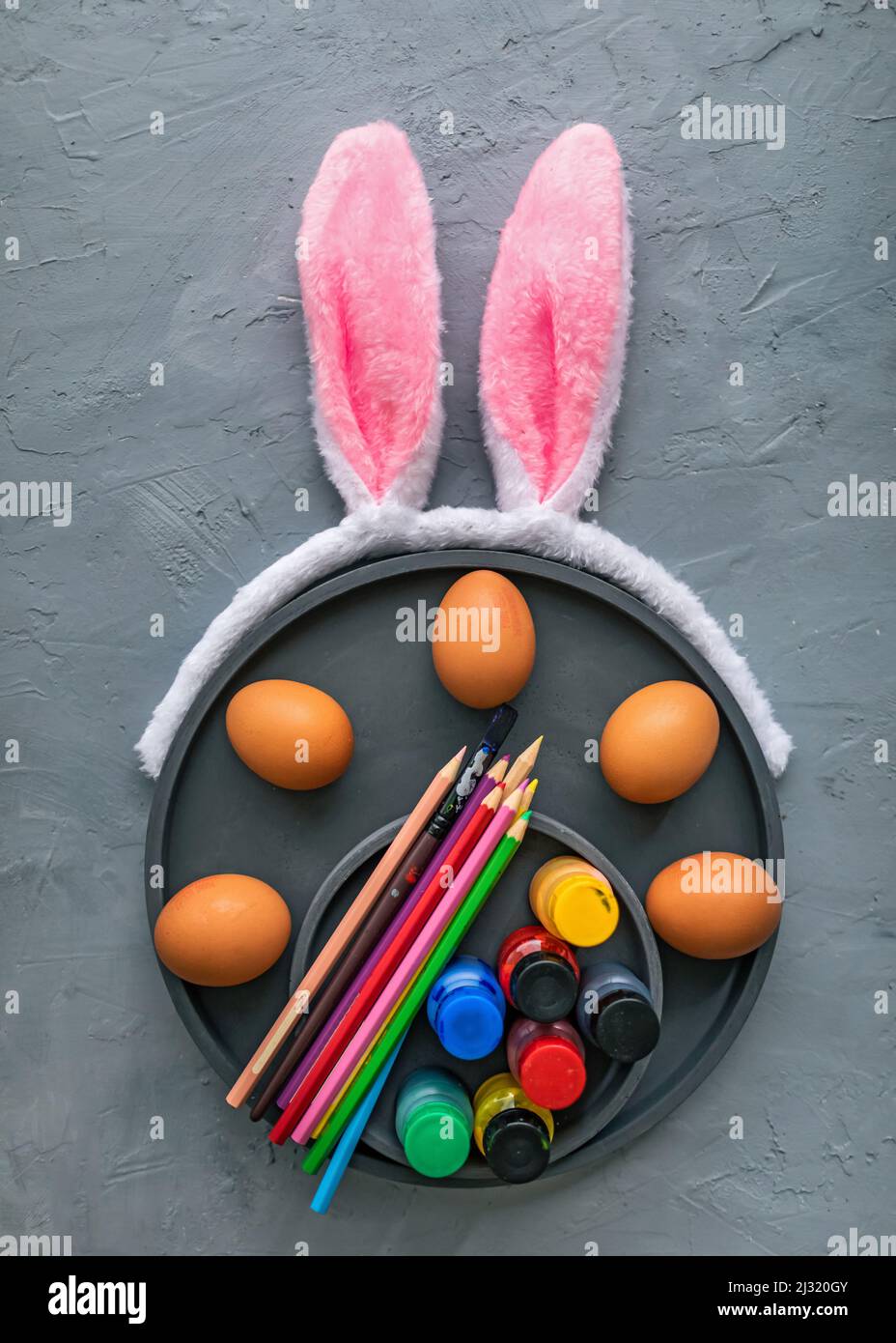 Vernici multicolore e pennelli sul piatto con uova. Uova da colorare per il concetto di Pasqua. Foto Stock