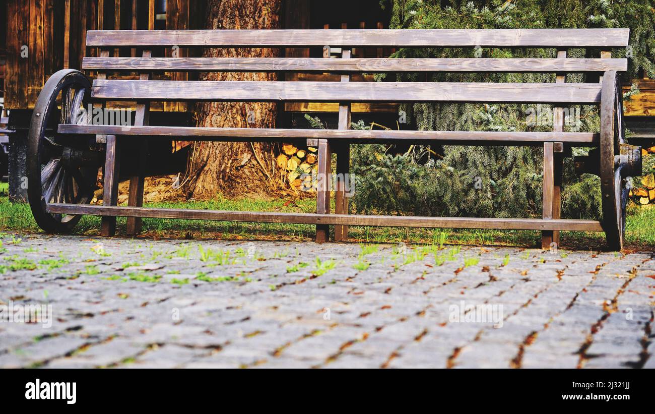 Panca in legno vintage con ruote carretto su pietre da pavimentazione Foto Stock
