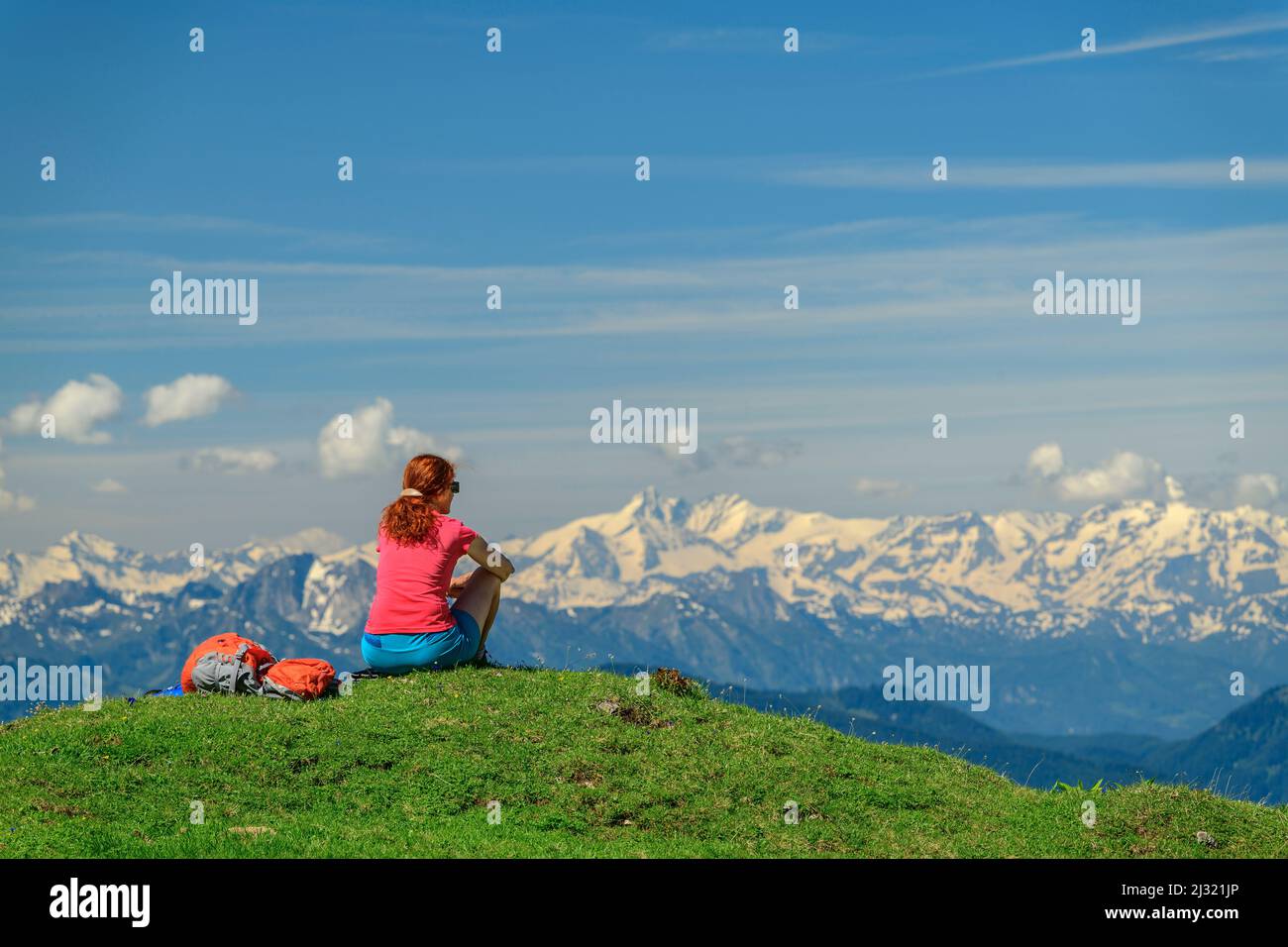 Donna mentre escursioni si siede sul prato e guarda Hohe Tauern con Grossglockner, da Rinderfeld, Dachstein, patrimonio mondiale dell'UNESCO Hallstatt, Salisburgo, Austria Foto Stock