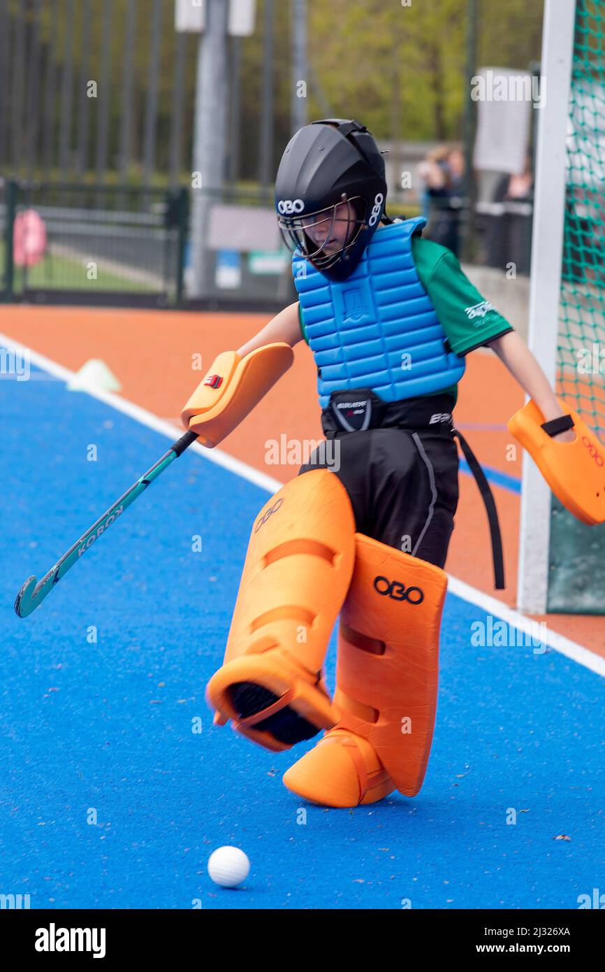 I Paesi Bassi, un portiere di una squadra di hockey di un bambino, calcia la palla con il piede. Nell'hockey da campo, il portiere indossa generalmente un'estesa protezione Foto Stock