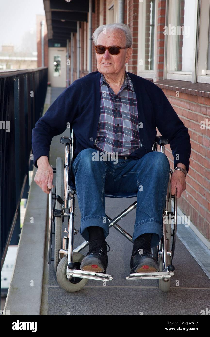 Olanda, uomo cieco in sedia a rotelle sulla sua strada di ritorno a casa in un appartamento edificio al quarto piano. La sua casa è accessibile a causa di un piano, no d Foto Stock