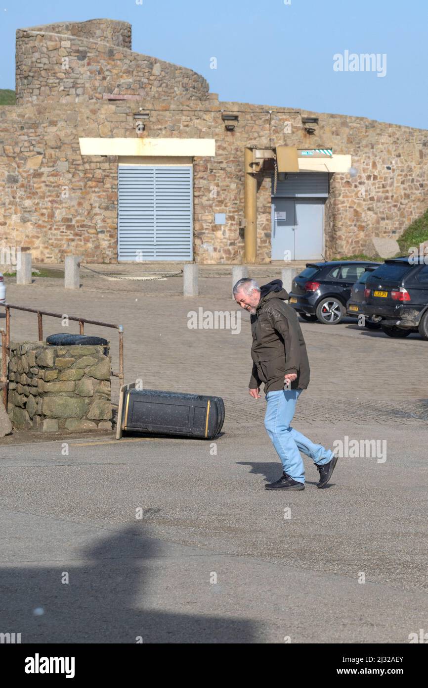 Un uomo che lotta per attraversare un parcheggio in forte vento portato nel Regno Unito da Storm Eunice. Newquay in Cornovaglia. Foto Stock