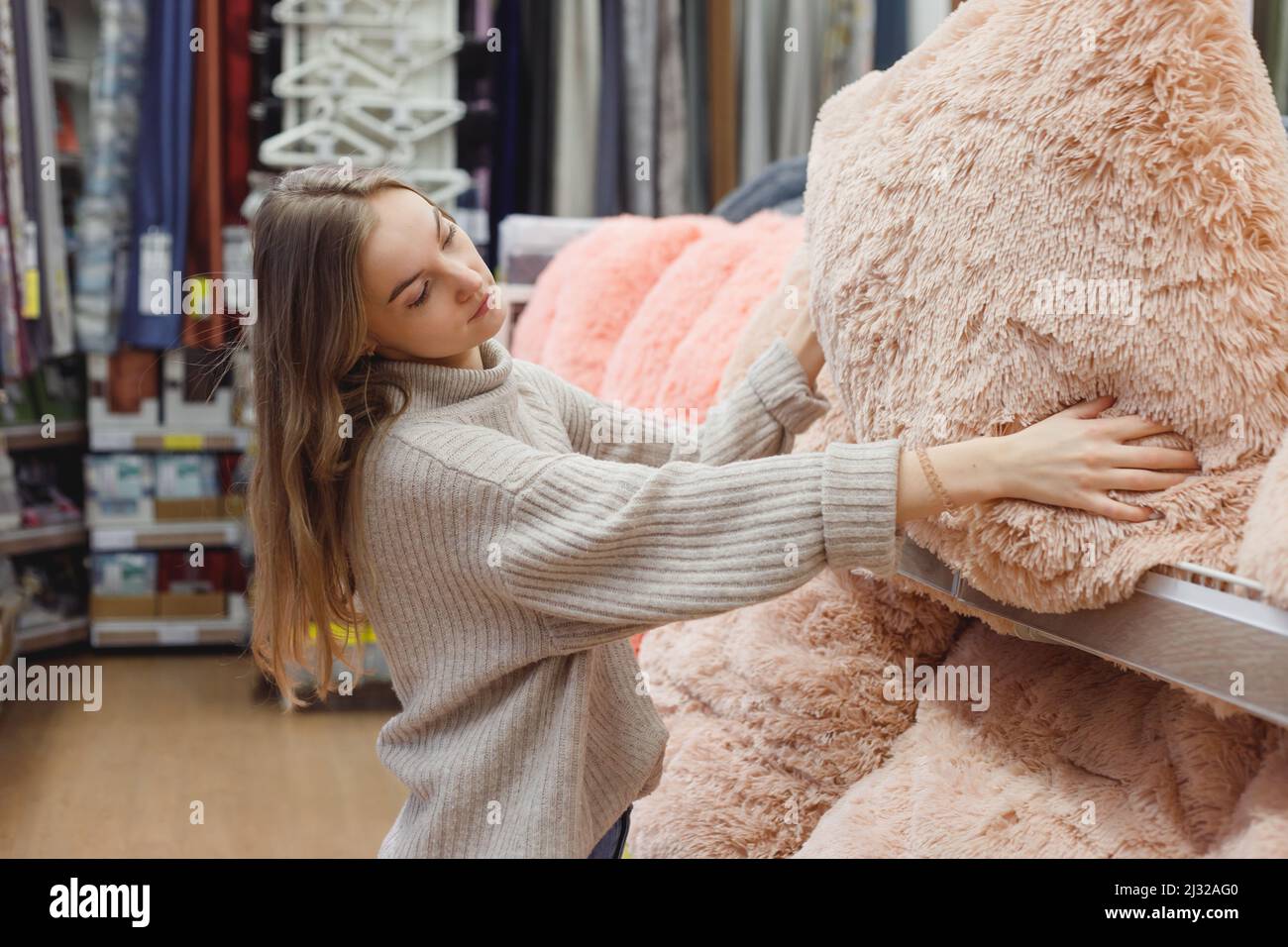 Giovane donna sceglie cuscino confortevole in negozio di articoli domestici, concetto di shopping. Foto Stock