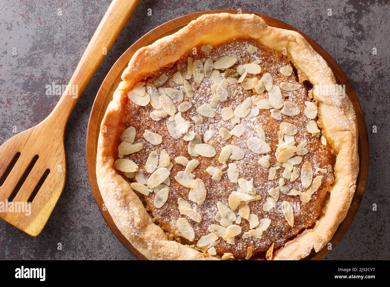 Dessert inglese Bakewell Pudding Cake con marmellata di lamponi e ripieno di pasta di uova e mandorle da vicino sul tavolo. Vista dall'alto orizzontale Foto Stock