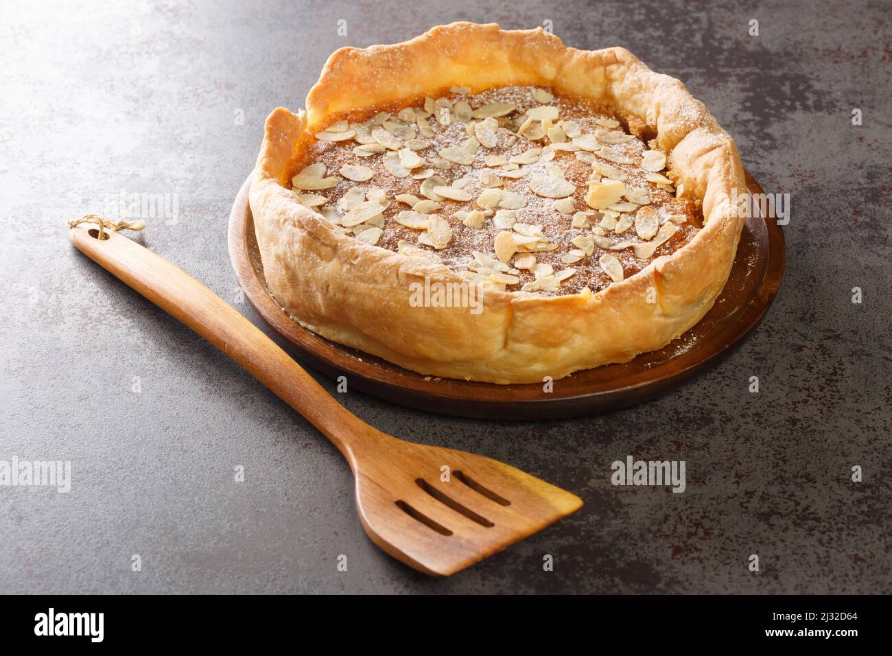 Bakewell Pudding è una torta dolce, una scatola di pasticceria croccante ripiena di spugna di mandorle dolci sopra la marmellata di lamponi primo piano sul tavolo. Orizzontale Foto Stock
