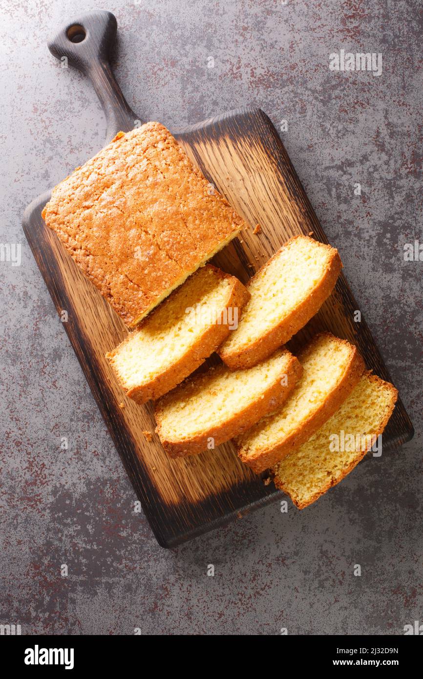 Tagliare a fette Madeira Cake Closeup su un tagliere di legno sul tavolo. Vista dall'alto verticale Foto Stock