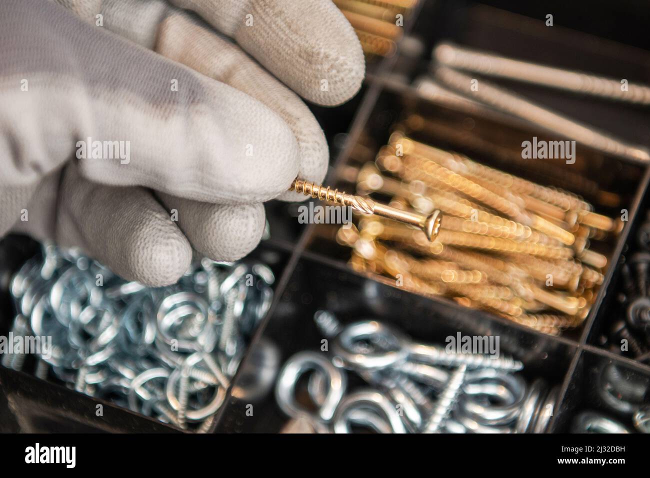 Scelta delle viti di metallo giuste primo piano concettuale. Il lavoratore tiene la vite d'oro in mano. Tema industriale. Foto Stock